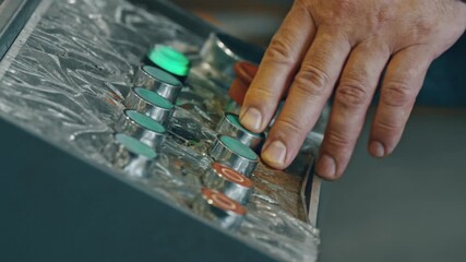 Hand operating industrial control panel, pressing buttons to operate machinery. Worker interacts with technology in factory setting