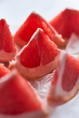 Freshly cut grapefruit segments arranged on a plate with natural light illuminating the textures
