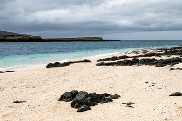 Scenic view of a rocky beach with clear turquoise water under a cloudy sky in Isle of Skye