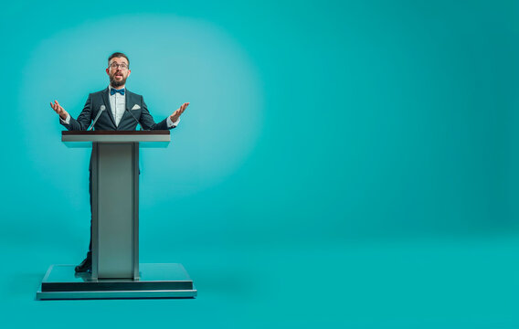 homme en train de faire un discours derri&egrave;re un pupitre - fond bleu	
