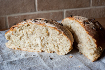 Homemade sourdough bread chopped, slices, Italian recipe, baked with a crust, on a gray cloth and brickwork background