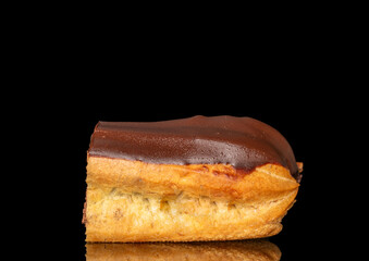 One half of an eclair with cream, macro, isolated on a black background.