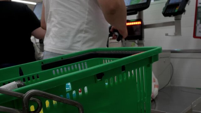 Unrecognizable man scanning products at a self-service checkout and pays for her purchase. Buyer scans barcoded products from grocery cart. Close-up