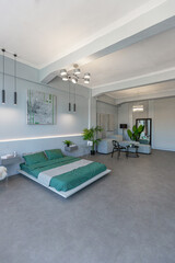 stylish discreet interior of the sleeping area in a modern studio in white-gray colors with green plants. daylight and no people inside