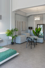 stylish discreet interior of the sleeping area in a modern studio in white-gray colors with green plants. daylight and no people inside