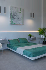 stylish discreet interior of the sleeping area in a modern studio in white-gray colors with green plants. daylight and no people inside