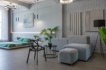 stylish discreet interior of the sleeping area in a modern studio in white-gray colors with green plants. daylight and no people inside