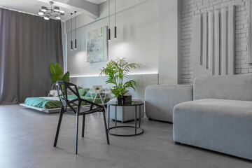 stylish discreet interior of the sleeping area in a modern studio in white-gray colors with green plants. daylight and no people inside