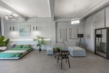 stylish discreet interior of the sleeping area in a modern studio in white-gray colors with green plants. daylight and no people inside