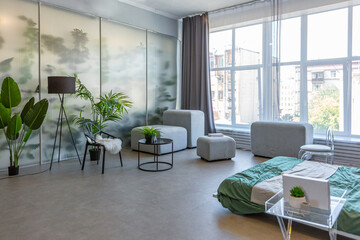 stylish discreet interior of the sleeping area in a modern studio in white-gray colors with green plants. daylight and no people inside