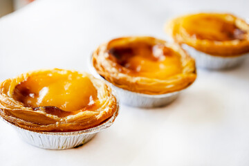 Pastel de nata or Pastel de Belém. Bright, golden, crispy traditional Portuguese dessert on a white background. Copy space for the text. Banner. Advertising 