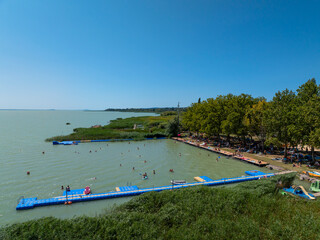 Beach in Lake Balaton. People bathing in the water of lake in  hot summertime. There are many...