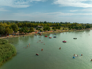 Beach in Lake Balaton. People bathing in the water of lake in  hot summertime. There are many...