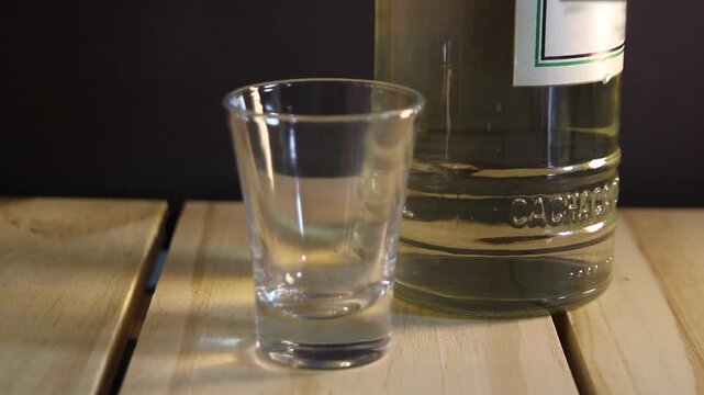 Close of of a traditionla cacha&ccedil;a glass cup with a bottle in the background and a close up in the cup. Cacha&ccedil;a is a Brazilian traditional alchoolic drink