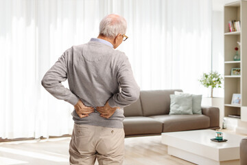 Rear view shot of an elderly man in pain holding his lower back