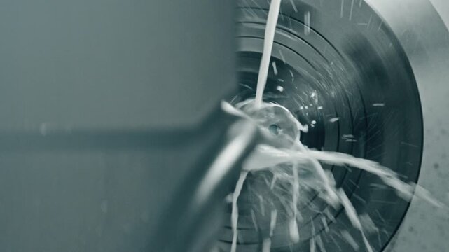 Close-up of a cnc machine drilling metal with coolant fluid splashing, showcasing high precision engineering in an industrial setting