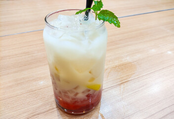 A creamy yogurt drink layered with strawberry jam and jelly, elegantly garnished with fresh mint...