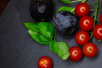 Juicy, aromatic, bright cherry tomatoes, sun-dried basil and figs on a black stone plank. Copy space the text. Banner. Background