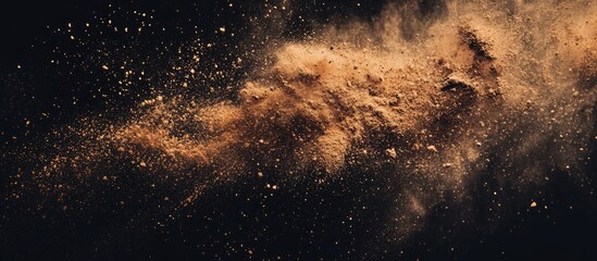 Obraz premium Abstract brown powder scattered on a black background capturing the motion of brown powder bursting and spreading across the black surface. with copy space image. Place for adding text or design