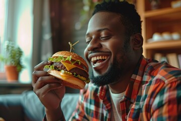 Man holding a burger with cheese in a cozy room.