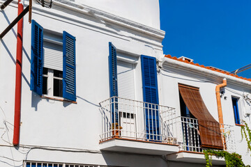 A picturesque example of Mediterranean architecture featuring vibrant blue shutters on a...