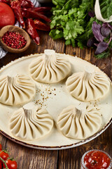 Traditional Georgian Khinkali Dumplings on Wooden Plate with Herbs, Spices, and Vegetables
