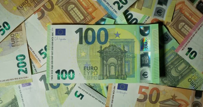 Euro banknotes of different denominations are randomly lying on the table. View from above