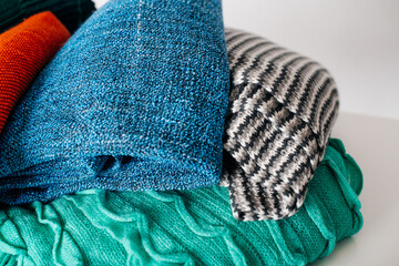 A stack of warm, knitted blankets in various colors and patterns, ideal for cozy and home-related visuals.