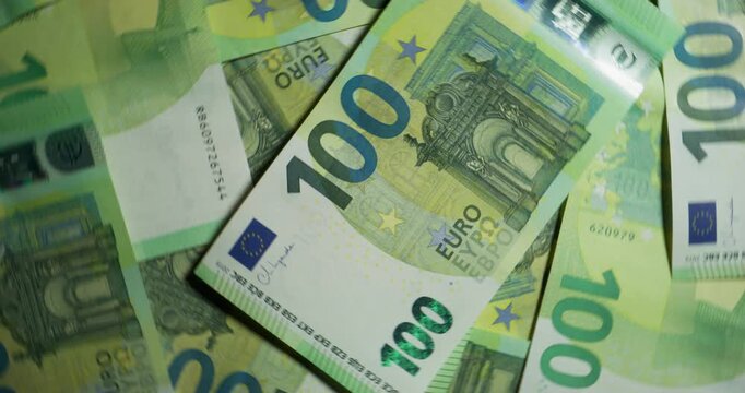 One hundred euro bills are randomly placed on the table. View from above. The camera moves in a circle