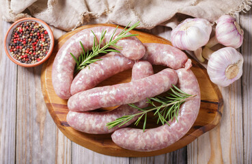 Fresh sausages with rosemary and ingredients for cooking, top view