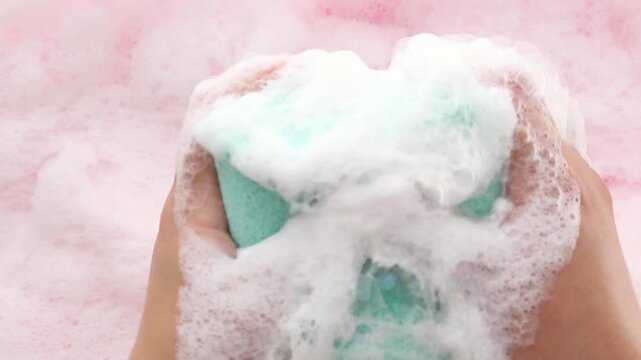 Women's hands in thick foam smooth out the washcloth and slowly squeeze it, creating a lot of foam and creating a visual and sound soothing, relaxing effect. Close-up. Asmr.Part 2