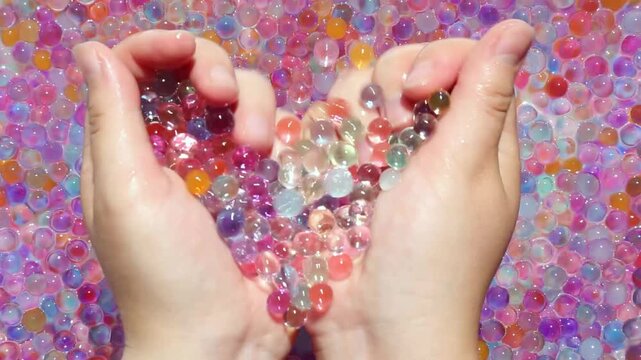 The girl's hands slowly pick up colored orbis in her palms and gently squeeze them and calmly scatter them. View from above. Part 3. Asmr. Visual and sound effects for relaxation and peace.