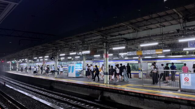 Commuters waiting on a platform at Tokyo's Shinagawa Station at night