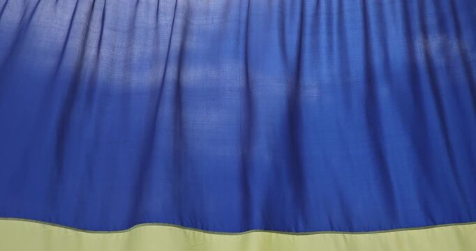 Blue yellow flag of Ukraine flutters due to wind as symbol of freedom invincibility