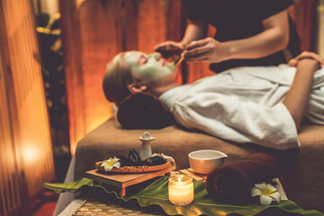 Serene ambiance of spa salon, woman customer indulges in rejuvenating with luxurious face cream massage with warm lighting candle. Facial skin treatment and beauty care concept. Quiescent