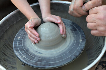 Potter helps to the child at a pottery master class.