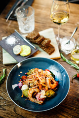 Warm salad with Argentinian king prawns. Almond potato, mini romaine lettuce, carrot, cherry tomato, pesto, black root chips, caramelized walnut, beet balsamic. Food served in modern restaurant