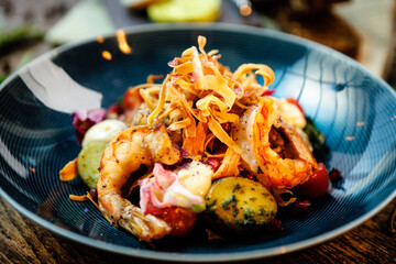 Warm salad with Argentinian king prawns. Almond potato, mini romaine lettuce, carrot, cherry tomato, pesto, black root chips, caramelized walnut, beet balsamic. Food served in modern restaurant