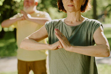 Medium close up of toned arms of senior woman in open hand vs closed fist position, senior man...