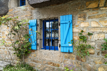 Les chaumières de Kérascoët en été, avec leurs toits de chaume et leurs fenêtres à petits carreaux entourées de volets bleus et de rosiers, dégagent une atmosphère romantique et bucolique.