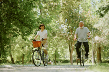Obraz premium Sporty senior wife and husband riding bikes to stay healthy during retirement