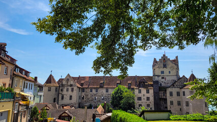 Obraz premium A picturesque view of a medieval castle Burg Meersburg and the brick roofs of the old town on a sunny summer day. The Burg Meersburg in framing green linden trees. Meersburg, Germany,