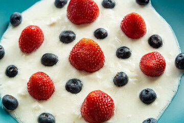 Berries strawberries and blueberries in a blue plate with thick whipped cream top view