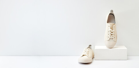 Pair of stylish sneakers on white background with geometric podium