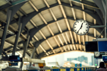 clock at sky train terminal platform screen in the back and train is coming day time