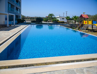 A sparkling private swimming pool surrounded by palm trees situated between residential buildings