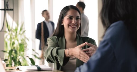 Happy woman passed successfully job interview shake hands female HR finish meeting in company office. Manager make deal handshake client express respect for cooperation. Business relation, partnership