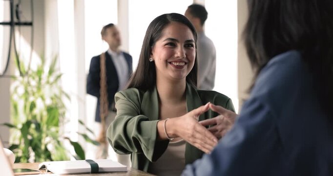 Happy woman passed successfully job interview shake hands female HR finish meeting in company office. Manager make deal handshake client express respect for cooperation. Business relation, partnership