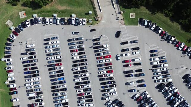 Entrance to large parking lot full of electric, gas vehicles and cars driving around looking for available spot, people walking, parallel pattern, pavement marking number in metropolitan, flyover. USA