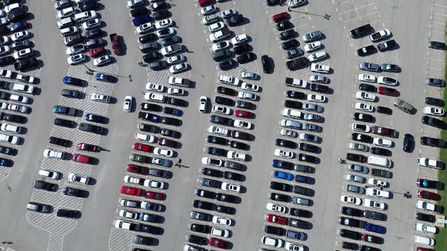 Few parking spots available and busy cars driving around looking for space in large outdoor lot in Arlington, Texas, people walking, modern parking management pavement marking number, flyover. USA